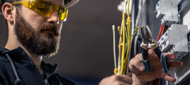 Male Electrician Works Switchboard with Electrical Connecting Cable - LC Electrical Services