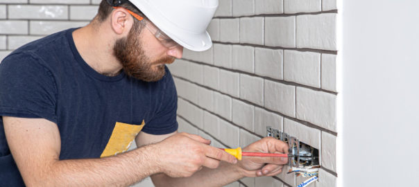 Electrician Construction Worker with Beard Overalls During Installation Sockets - LC Electrical Services