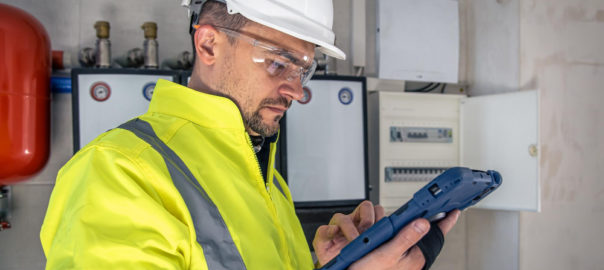 A man in a safety vest and hard hat holding a tablet, ensuring a secure transition with our Newport-specific Moving In Electrical Checklist.